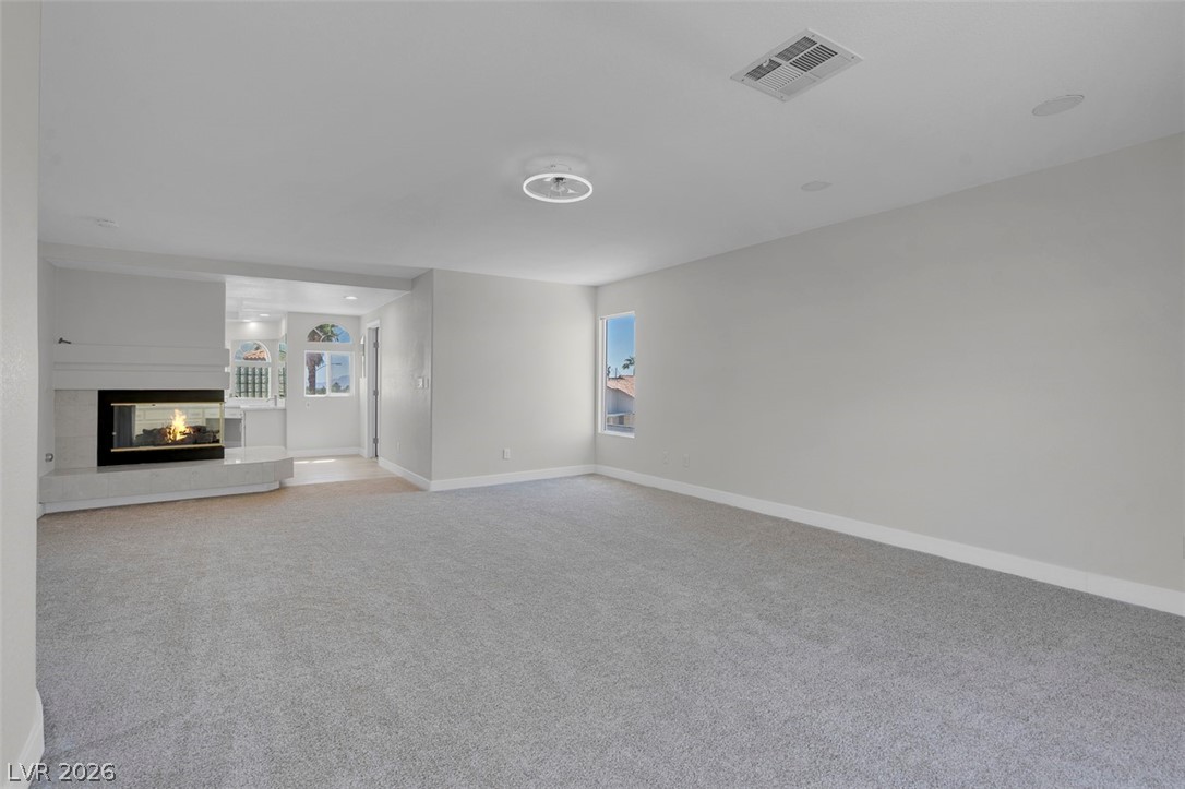 3604 North Campbell Road Las Vegas, NV 89129 - Photo 33 of 54 Unfurnished living room with carpet floors, baseboards, a multi sided fireplace, and plenty of natural light