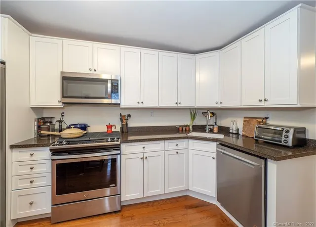 a kitchen with granite countertop white cabinets and stainless steel appliances