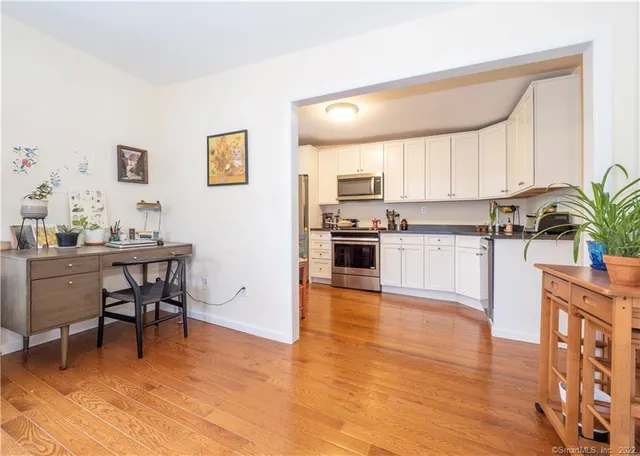 a kitchen with stainless steel appliances a dining table chairs stove refrigerator and cabinets