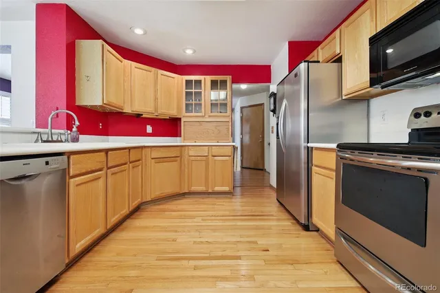 a kitchen with stainless steel appliances a sink cabinets and wooden floor