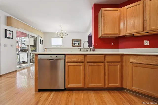 a kitchen with stainless steel appliances granite countertop a refrigerator a sink dishwasher and wooden cabinets with wooden floor