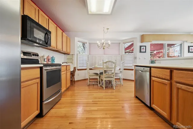 a kitchen with stainless steel appliances granite countertop a stove top oven a sink dishwasher and white cabinets with wooden floor