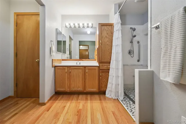 a view of a hallway with wooden floor and a bathroom