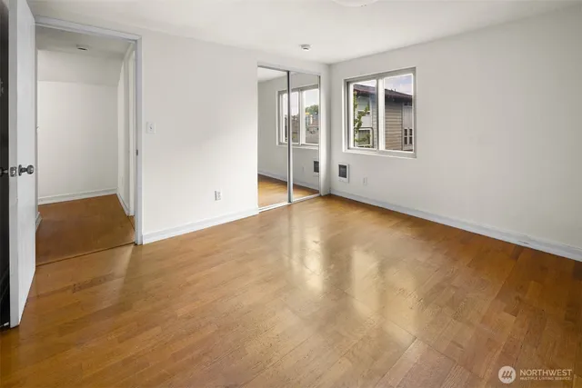 an empty room with wooden floor and windows