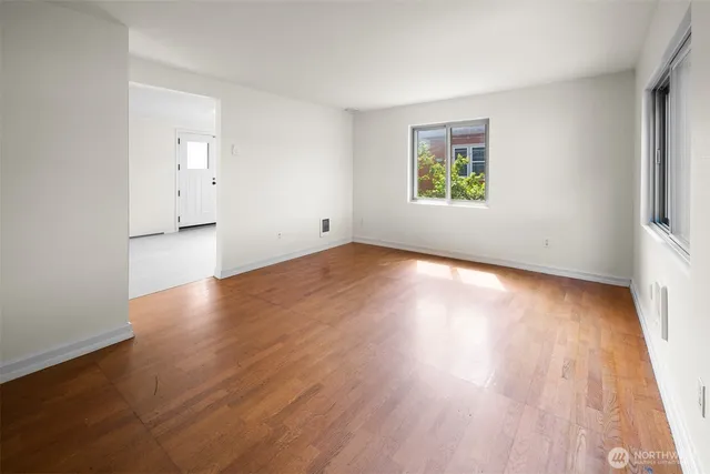 an empty room with wooden floor and windows