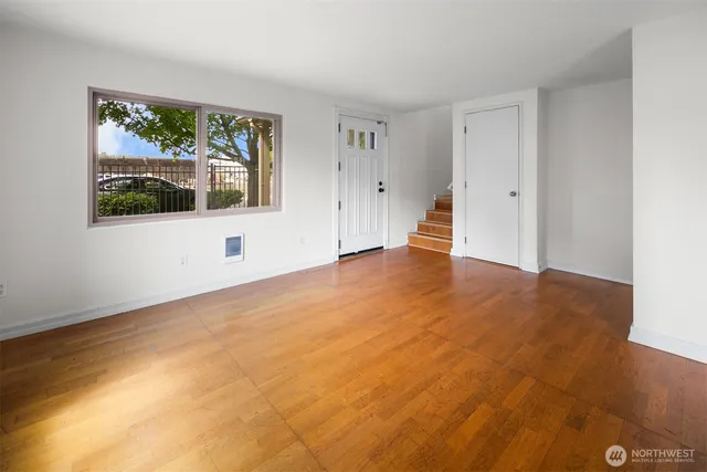 a view of an empty room with wooden floor and window