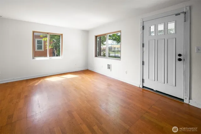 an empty room with wooden floor and windows