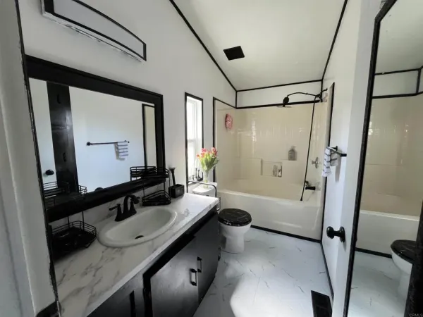 a bathroom with a granite countertop sink a toilet a mirror and shower