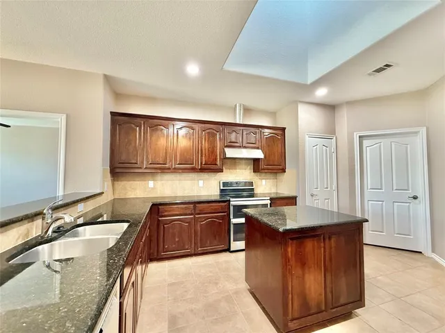 a kitchen with granite countertop a sink stove and cabinets