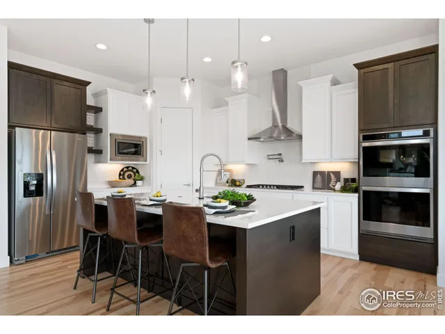 a kitchen with stainless steel appliances a dining table chairs refrigerator and microwave