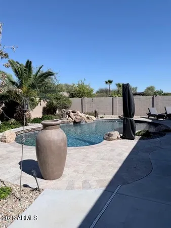 a view of a patio with table and chairs under an umbrella with a small yard