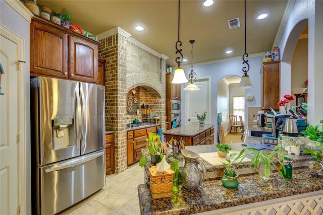 a kitchen with stainless steel appliances granite countertop a refrigerator a oven a sink and a dining table with wooden floor