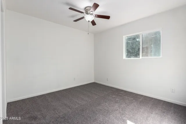 an empty room with a window and a fan