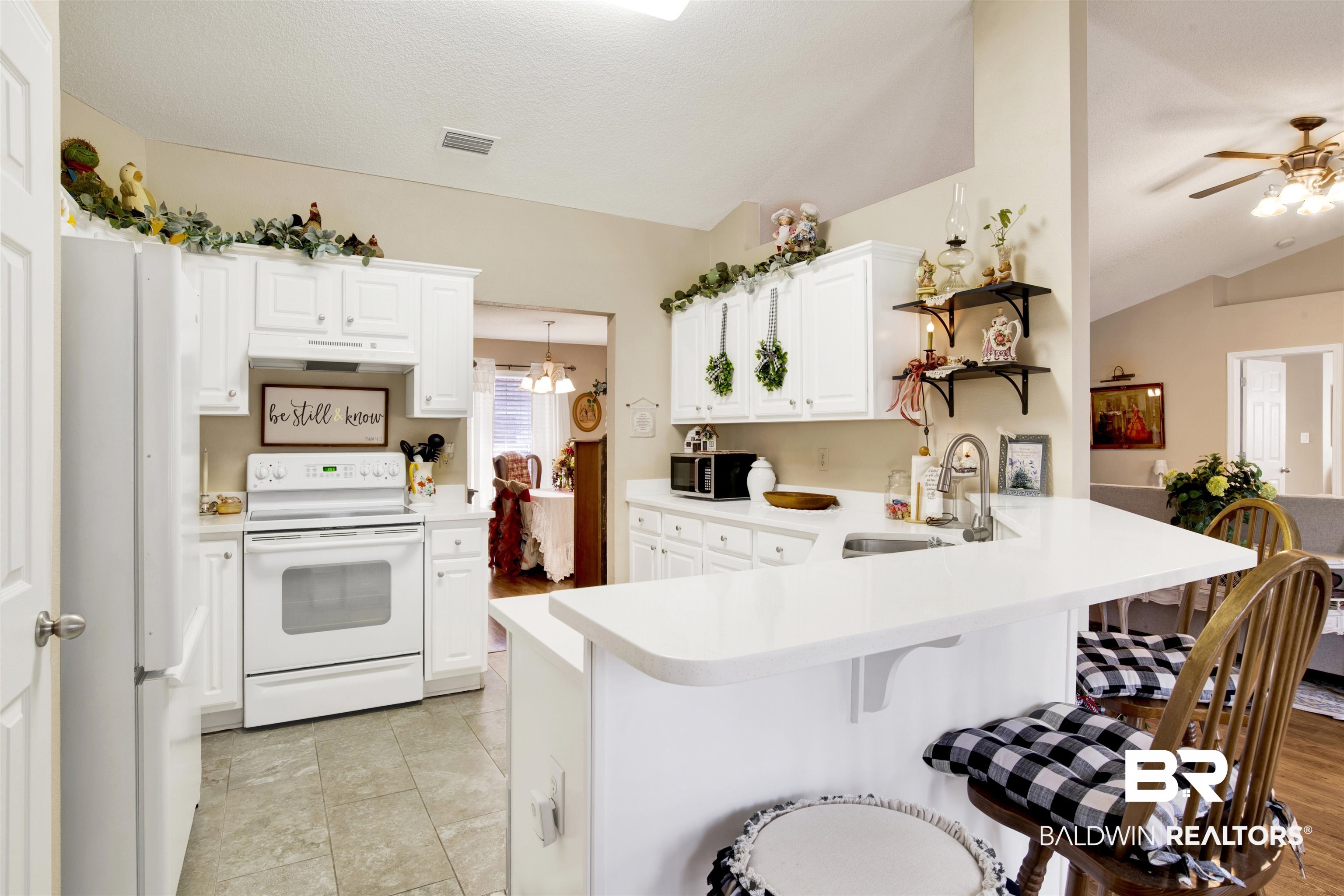 11697 Balsam Court Daphne, AL 36527 - Photo 13 of 31 Kitchen with sink, a breakfast bar area, white cabinets, kitchen peninsula, and white appliances