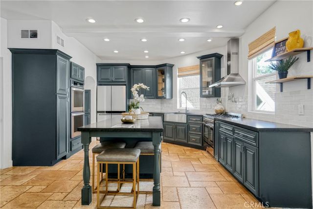 a kitchen with stainless steel appliances a dining table chairs stove refrigerator and cabinets