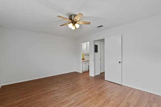 a view of empty room with wooden floor and fan