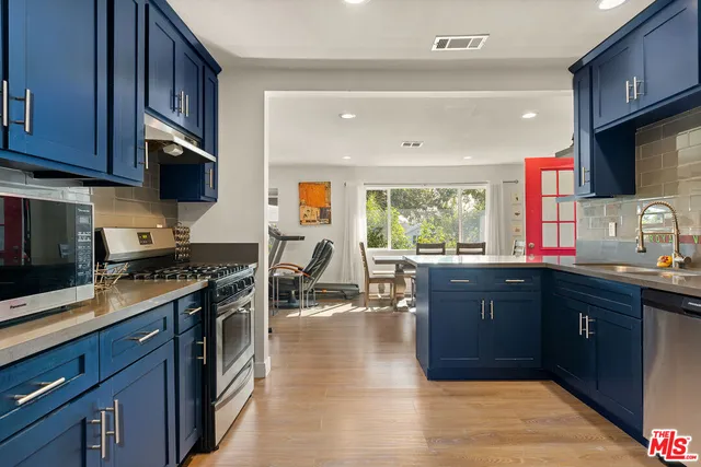 a kitchen with stainless steel appliances granite countertop a stove top oven a sink dishwasher and wooden cabinets with wooden floor