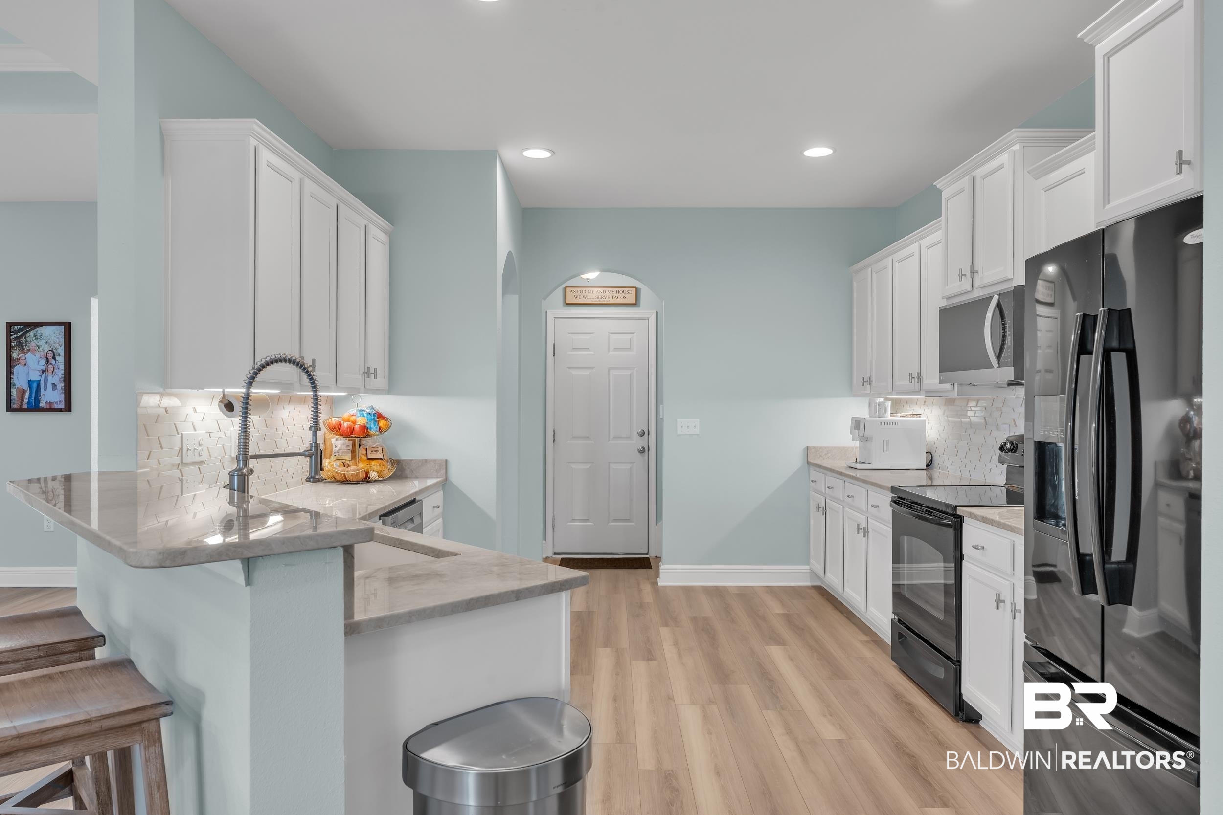 7109 Rocky Rd Loop Gulf Shores, AL 36542 - Photo 15 of 30 Kitchen with white cabinetry, black appliances, decorative backsplash, and a breakfast bar