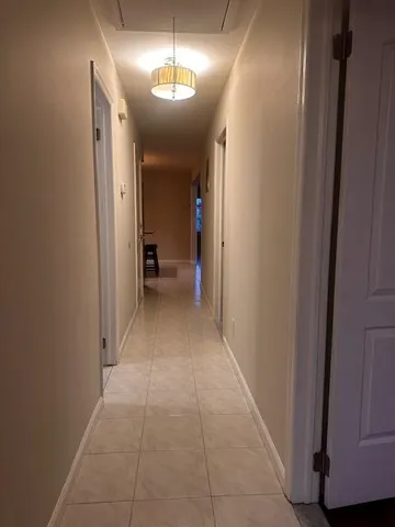 a view of a hallway with wooden floor and chandelier