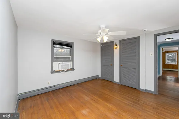 an empty room with wooden floor chandelier fan and windows