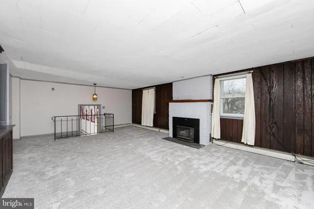 a view of a livingroom with a fireplace cabinet and windows