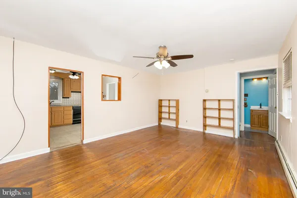 a view of a livingroom with wooden floor and a ceiling fan