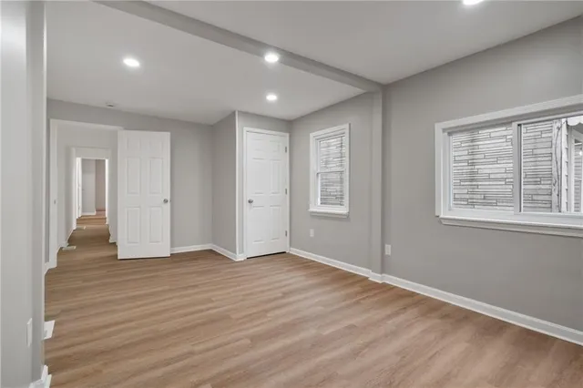 an empty room with wooden floor and windows