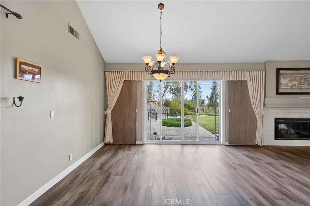 11056 Orchard View Lane Riverside, CA 92503 - Photo 10 of 50 a dining room with wooden floor a chandelier a flat tv screen and a fireplace