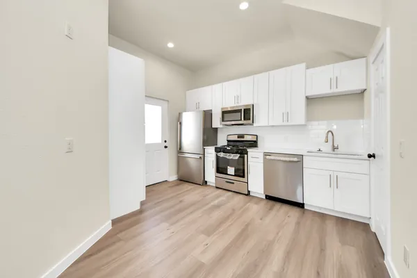a kitchen with a refrigerator a stove top oven and wooden floors