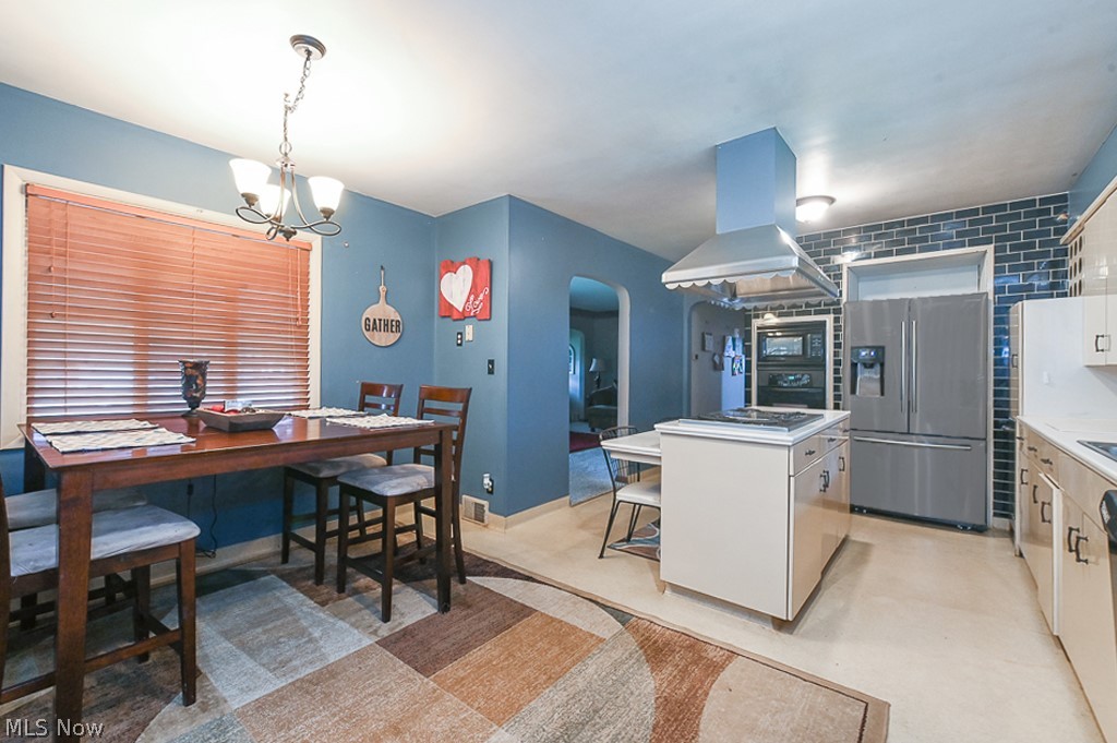 2819 Mayfair Road Akron, OH 44312 - Photo 8 of 49 Kitchen with stainless steel refrigerator with ice dispenser, a center island, a chandelier, island exhaust hood, and hanging light fixtures
