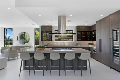 a kitchen with stainless steel appliances kitchen island granite countertop a dining table chairs and a refrigerator