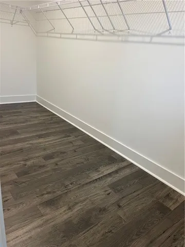 an empty room with wooden floor chandelier and windows