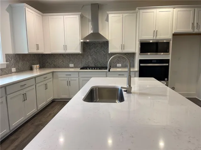 a kitchen with granite countertop a sink a stove and cabinets