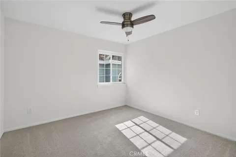 an empty room with windows and ceiling fan