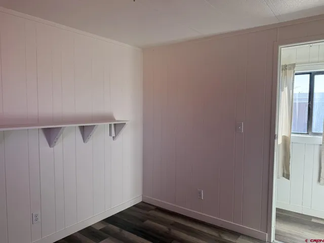 an empty room with wooden floor door and windows