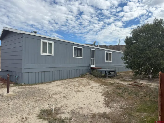 a backyard of a house with wooden fence and a tree