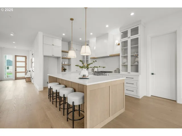 a kitchen with stainless steel appliances kitchen island granite countertop a sink and cabinets with wooden floor