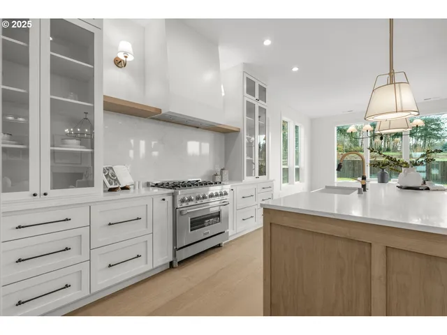 a kitchen with stainless steel appliances kitchen island granite countertop a sink a stove and a wooden floors