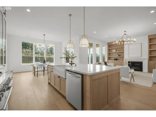 a kitchen with stainless steel appliances granite countertop a kitchen island a stove a sink a dining table and chairs with wooden floor