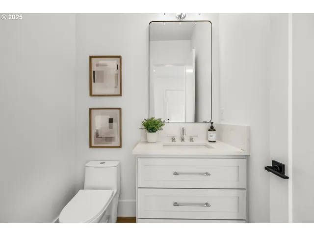 a bathroom with a toilet sink vanity and mirror