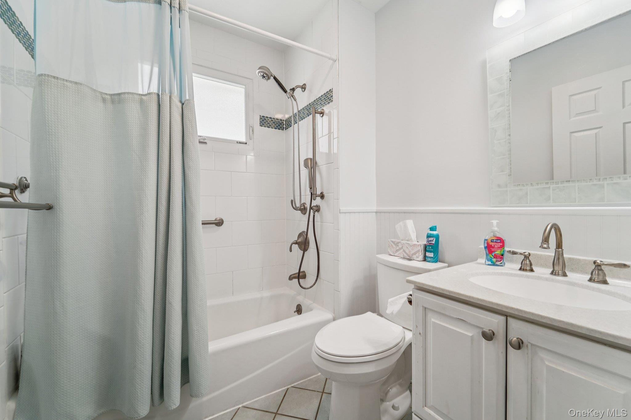 10 Ward Street Suffern, NY 10901 - Photo 21 of 34 Bathroom featuring shower / bath combo with shower curtain, vanity, wainscoting, and tile patterned floors