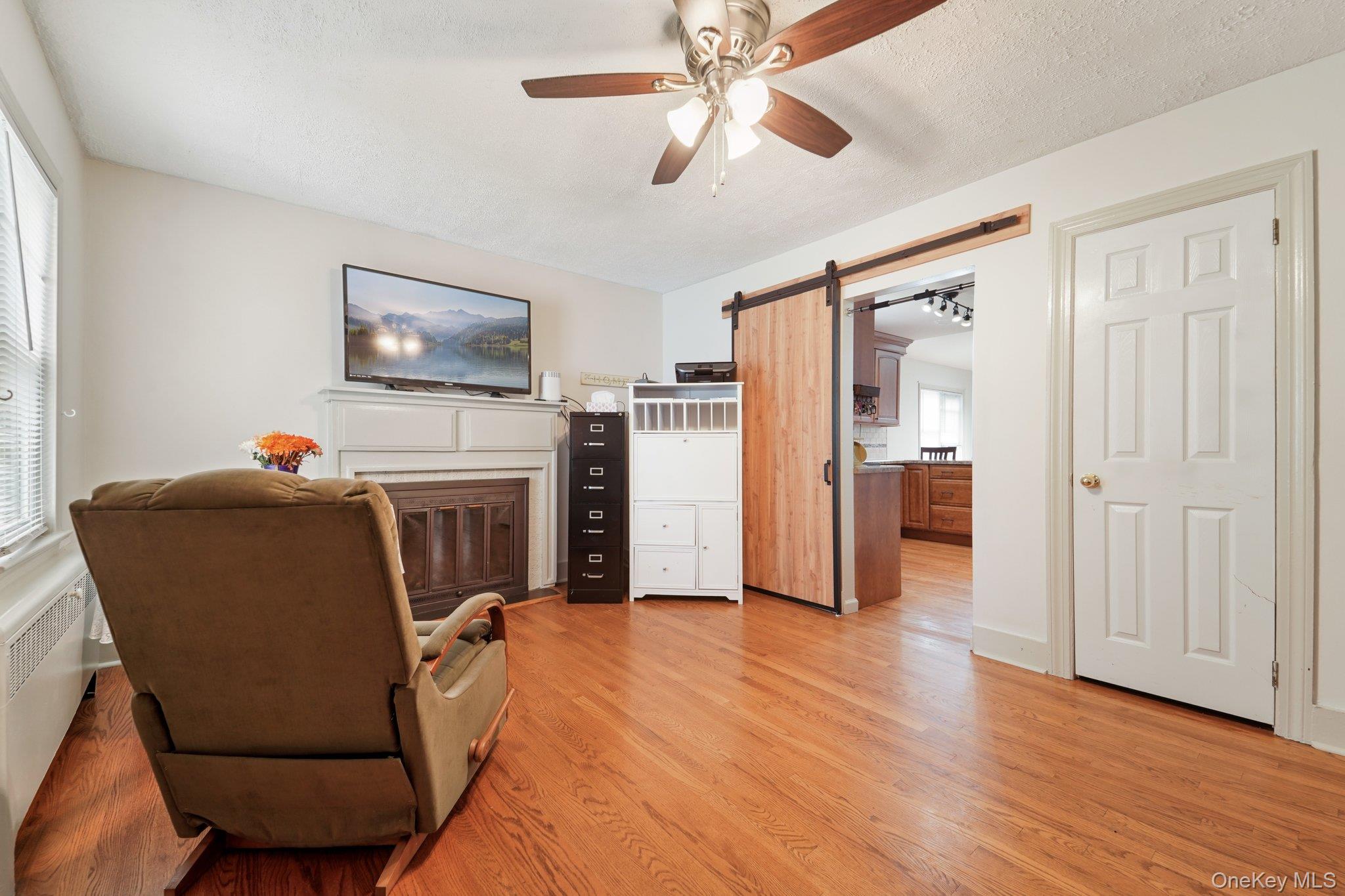 10 Ward Street Suffern, NY 10901 - Photo 5 of 34 Living area with ceiling fan, light wood finished floors, a barn door, and radiator