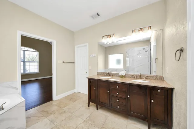 a spacious bathroom with a double vanity sink mirror and shower