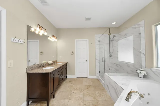 a bathroom with a granite countertop tub sink and mirror