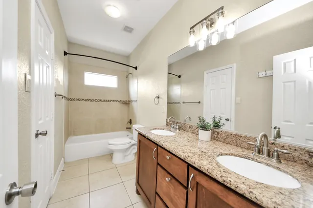 a bathroom with a granite countertop double vanity sink and a mirror