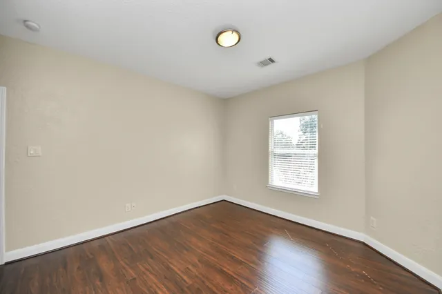 a view of an empty room with wooden floor