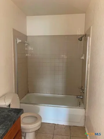 a bathroom with a granite countertop bathtub shower sink and toilet