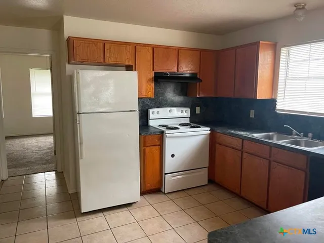 a kitchen with a refrigerator sink and cabinets
