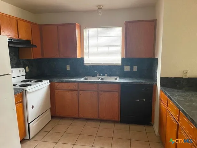 a kitchen with granite countertop a sink a stove and a microwave