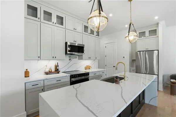 a kitchen that has a sink a microwave oven a stove and a dining table with wooden floor